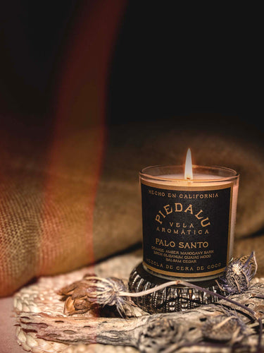 Our Palo Santo 7 ounce candle with a beautiful flame and burlap backdrop